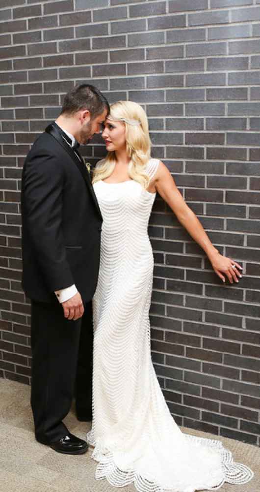 bride and groom against brick wall