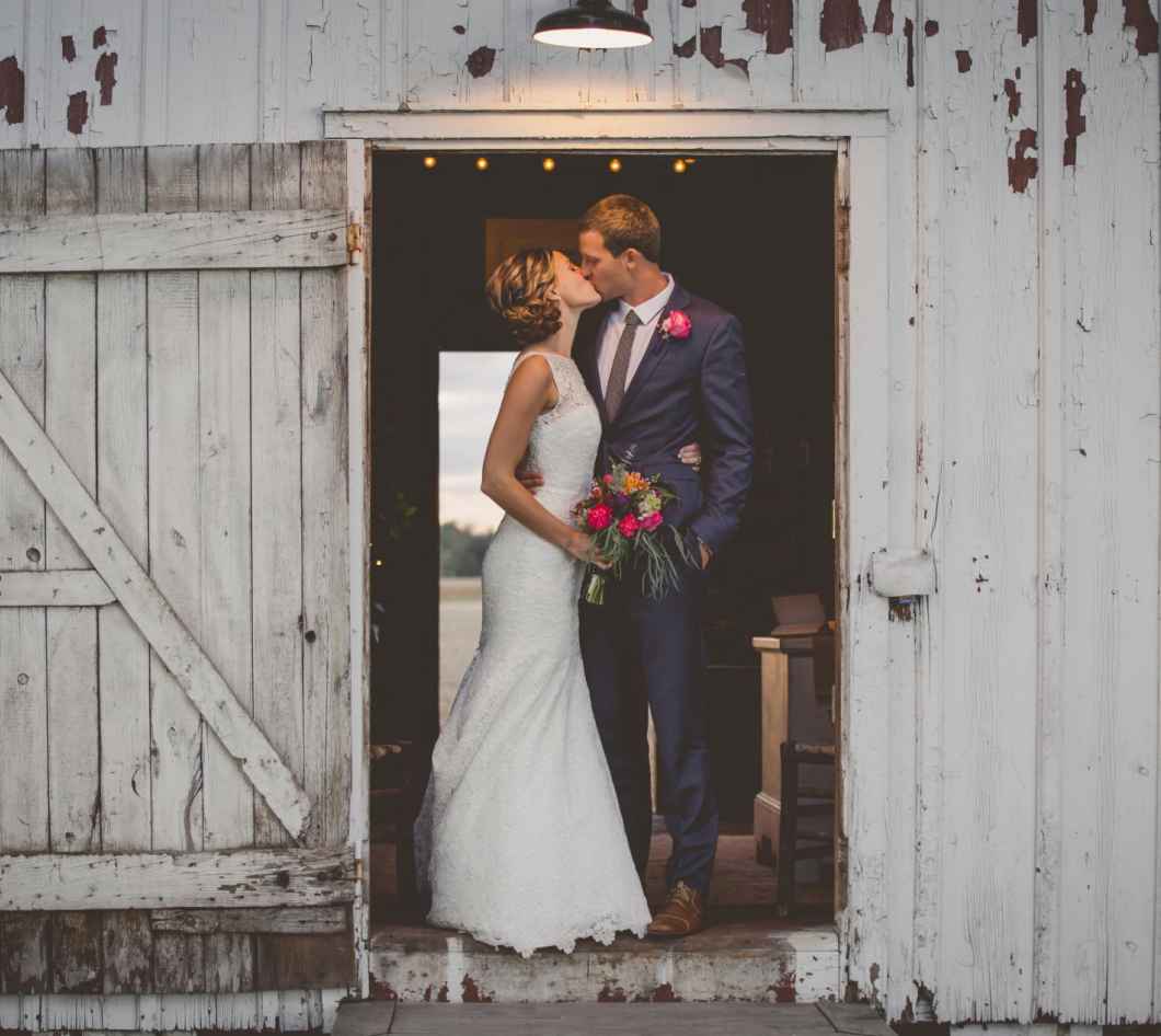 couple posing inside wedding barn