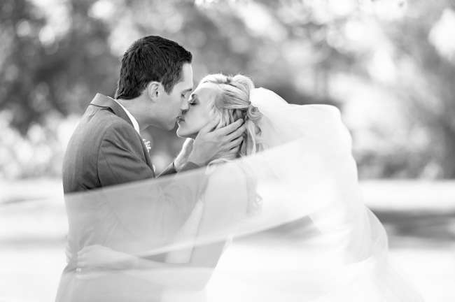 Bride & Groom Kissing as Bride's Veil Blows in Front of Them