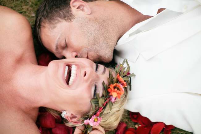 Groom Kisses Bride's Cheek While Laying in the Grass