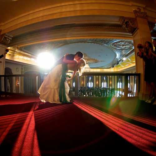 Wedding kis on balcony overlooking ballroom
