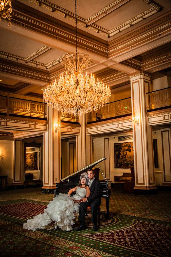 Bride & Groom Sitting at a Piano Under a Chandelier