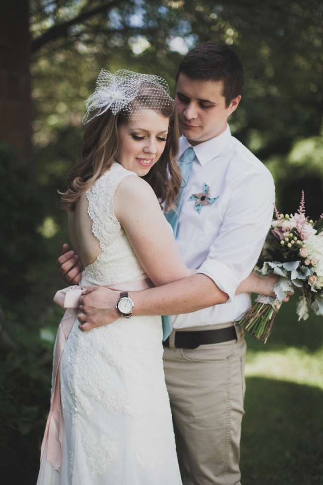 Groom With Pinwheel Boutonniere Embraces His Bride