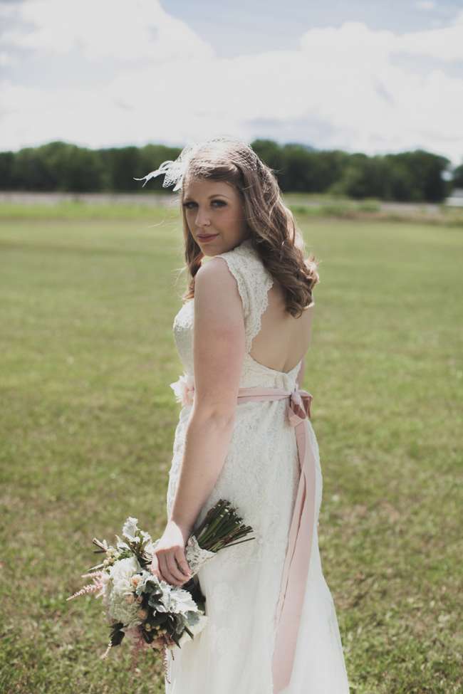 Bride Looking Over Her Shoulder in Open Field | WeddingDay Magazine