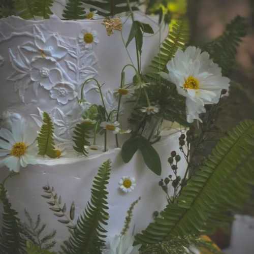 4-tier white wedding cake with buttercream textured florals and fresh ferns and florals with gold accents